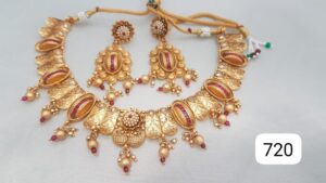 Gold necklace with red accents and matching earrings featuring intricate designs and embellishments.