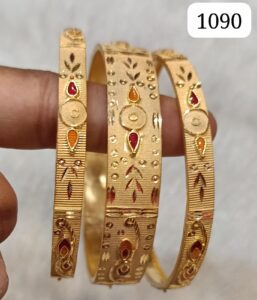 Three gold bangles featuring intricate patterns and colorful embellishments in red and orange.