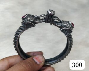 Silver bangle featuring elephant heads with red gemstones, showcasing intricate detailing and craftsmanship.
