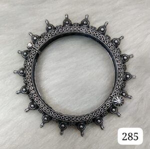 Silver decorative bangle featuring intricate designs and circular embellishments around the edge.