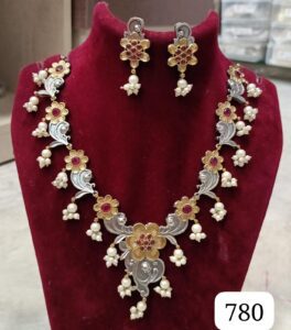 Traditional necklace featuring silver and gold design with floral motifs and pearl accents, accompanied by matching earrings.