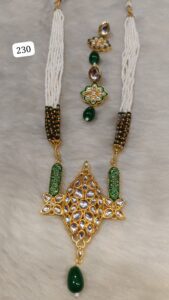 Traditional Indian necklace set featuring a large ornate pendant and matching earrings with green and gold accents.