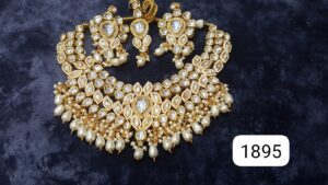 Gold necklace set adorned with pearls and intricate stonework, accompanied by matching earrings.