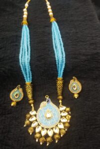 Blue beaded necklace with gold accents and matching earrings featuring intricate designs.