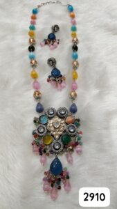 Colorful beaded necklace with a large pendant and matching earrings displayed on a soft surface.