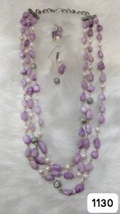 Purple beaded necklace with silver accents and matching earrings displayed on a soft surface.