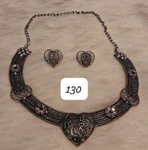 Silver necklace with heart-shaped pendant and matching earrings displayed on a light background.