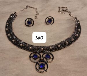 Silver necklace with blue stones and matching earrings featuring circular designs and pearls.