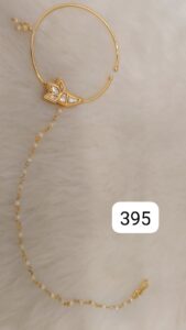 Gold bangle featuring a decorative charm and a chain attachment with small beads.