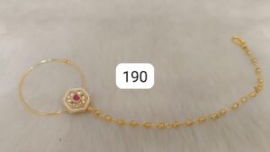 Gold bracelet featuring a hexagonal pendant with red and white embellishments and a beaded chain.