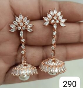 Pair of rose gold earrings featuring pearls and crystal embellishments, held in a hand.