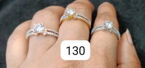 Three rings featuring central diamonds and intricate band designs displayed on a hand.