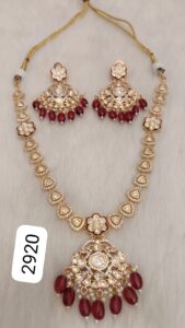 Gold jewelry set featuring a necklace and matching earrings with red beads and intricate designs.