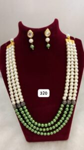 Multi-layered necklace featuring white pearls and green beads, accompanied by matching earrings.