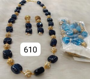 Navy blue beaded necklace and matching earrings with gold accents and additional loose beads in a plastic bag.