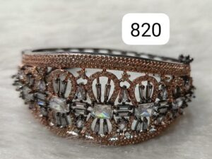 A decorative bracelet featuring intricate designs and various crystals set in a metal frame.