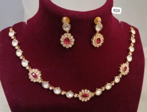 Gold jewelry set featuring a necklace with red and clear stones and matching earrings.