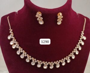 Gold necklace with pearl drops and matching earrings displayed on a maroon velvet bust.