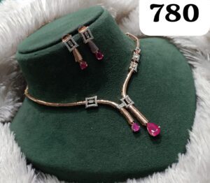 Gold and silver jewelry set featuring a necklace and earrings with ruby accents displayed on a green velvet stand.