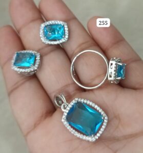 Jewelry set featuring a ring, pendant, and two earrings with blue stones and silver settings.