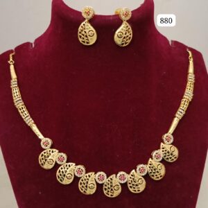 Gold necklace with intricate designs and matching earrings featuring red stones.