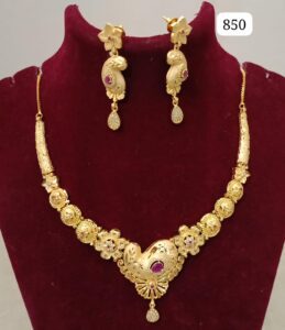 Gold necklace with intricate designs and matching earrings displayed on a velvet bust.