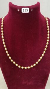 Gold necklace with alternating pearls displayed on a velvet bust.