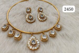 Gold necklace with gemstone accents and matching earrings displayed on a soft surface.