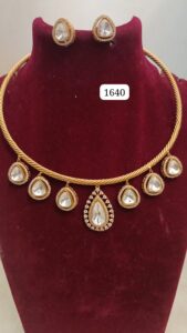 Gold necklace with teardrop-shaped pendants and matching earrings displayed on a velvet bust.
