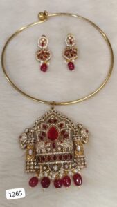 Gold necklace with intricate design featuring a large red stone and matching earrings with red accents.