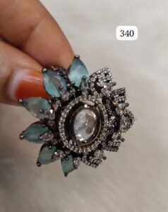 A decorative ring featuring a central clear stone surrounded by smaller gemstones and leaf-like accents.