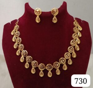 Gold necklace with leaf-shaped pendants and matching earrings displayed on a stand.