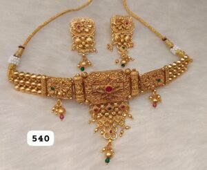 Gold necklace with intricate design and matching earrings featuring colored gemstones.
