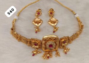Gold necklace with intricate designs and matching earrings featuring ruby accents.