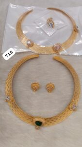 Gold necklace with intricate design and matching earrings featuring gemstones.