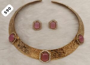 Gold necklace with intricate designs and pink stones, accompanied by matching earrings.