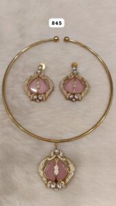 Gold jewelry set including a necklace and matching earrings with pink stones and decorative elements.