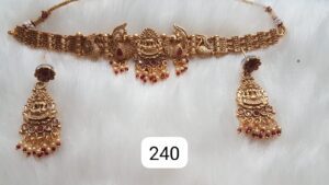 Gold necklace with intricate design featuring peacock motifs and matching earrings with red beads.